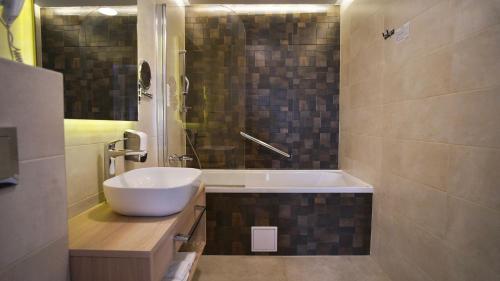 a bathroom with a sink and a bath tub at Hotel Gallus in Sesvete
