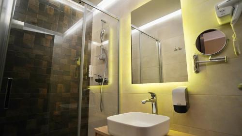 a bathroom with a sink and a shower with a mirror at Hotel Gallus in Sesvete