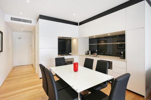 comedor con mesa blanca y sillas negras en New York on Riley - Split-Level Executive 2BR Darlinghurst Apartment with a New York Feel, en Sídney
