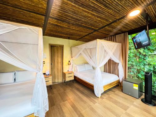 a bedroom with a canopy bed and a television at Rincon de la Sierra Minca in Minca