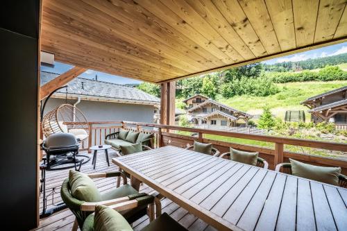 une grande terrasse avec une table et des chaises en bois dans l'établissement Apartment Edelweiss Les Gets - BY EMERALD STAY, aux Gets