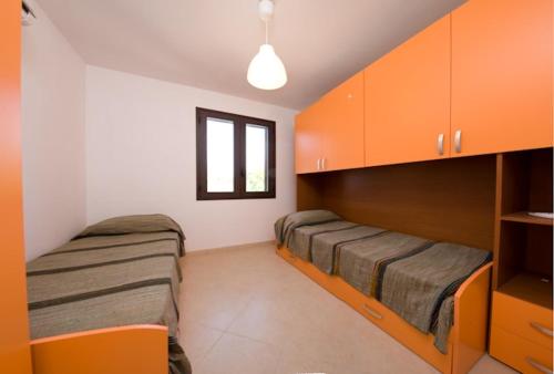 two beds in a room with orange cabinets at A Borgo Frigole 1 in Frigole