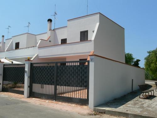 a white building with a gate and a fence at A Borgo Frigole 1 in Frigole