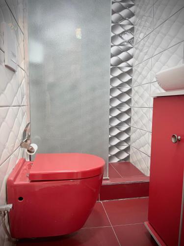 a red toilet in a bathroom with a shower at Hotel Heimli in Pristina