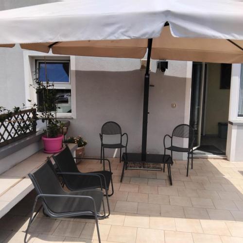 a patio with chairs and a white umbrella at La PERLA di LEVICO in Levico Terme