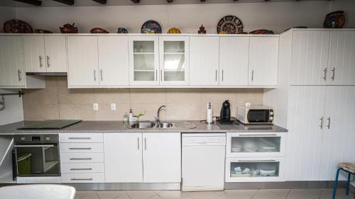a kitchen with white cabinets and a sink and a microwave at Monte dos Casarões Casa grande in São Luis