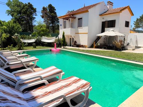 a swimming pool with lounge chairs in front of a house at Bam’s Farm in Alcobaça