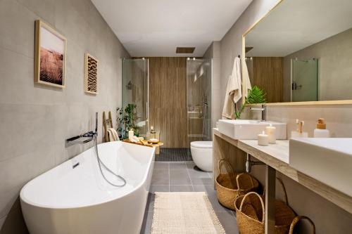 bagno con vasca, 2 lavandini e servizi igienici di Java - 3 bedroom and shared pool in Almagro a Madrid