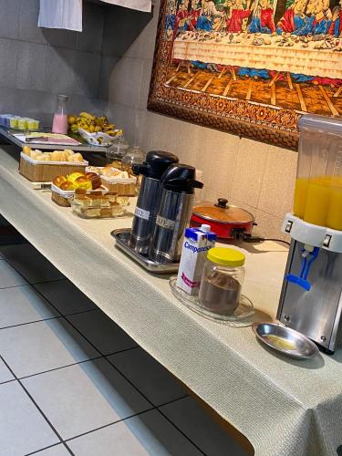 a buffet line with food and drinks on a counter at Elite Economy Hotel - Banheiro Compartilhado in Pará de Minas