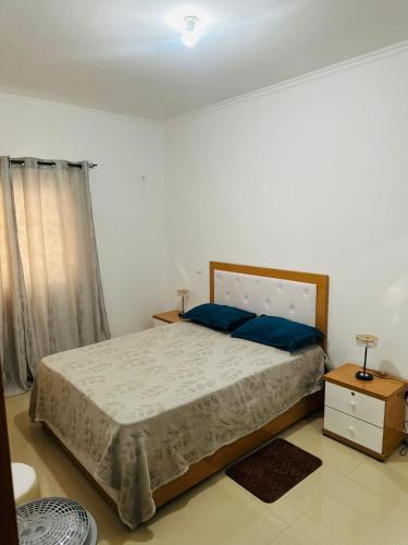 a bedroom with a large bed with blue pillows at jotapecomercio in Praia