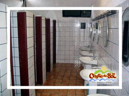 Un baño con cuatro lavabos y una fila de inodoros. en Hospedagem em Canasvieiras - Pé na Areia com Vista para o Mar, en Florianópolis