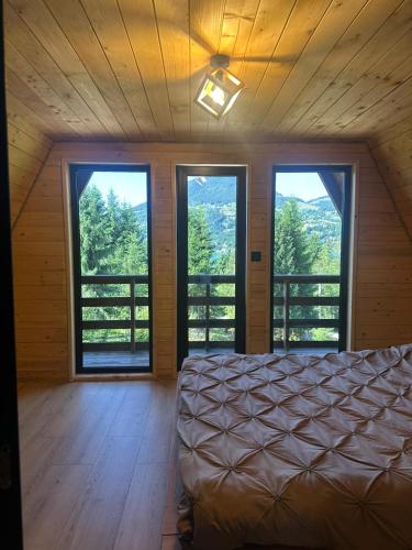 a bedroom with a bed in a room with windows at Rivera Cabin in Colibiţa