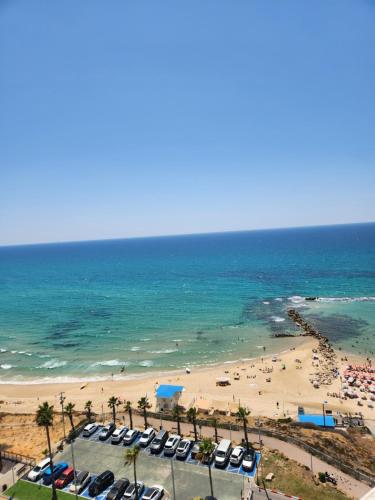 een uitzicht op een strand met een stel auto's bij הים של רז בטיילת בת ים in Bat Yam
