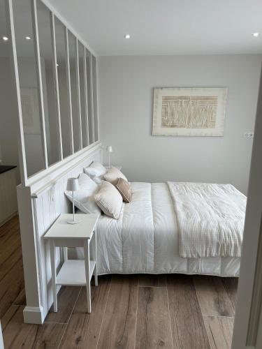 une chambre blanche avec un lit et une table dans l'établissement Le Clos Morgane Villa Mélissa, à Bretignolles-sur-Mer