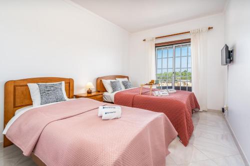 two beds in a room with a window at Classic & Spacious Flat w/ Balcony by HostWise in Monte Gordo