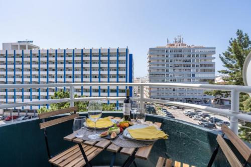 a table with a bottle of wine and glasses on a balcony at Classic & Spacious Flat w/ Balcony by HostWise in Monte Gordo