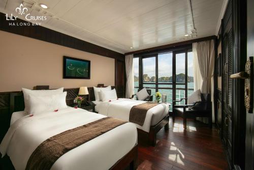 Una habitación de hotel con dos camas y una gran ventana. en Lily Cruise, en Ha Long