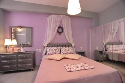 a purple bedroom with a large bed with pink sheets at Fouxia-Yellow in Skopelos Town