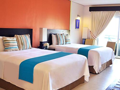 two beds in a hotel room with orange walls at Thunderbird Resorts - Poro Point in San Fernando