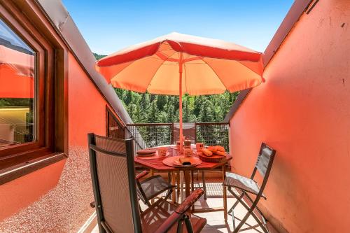a table with an umbrella on a balcony at Appartamento Alpine Inspiration - Happy Rentals in Cesana Torinese