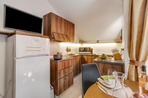 une cuisine avec un réfrigérateur blanc et une table dans l'établissement Appartamento Alpine Inspiration - Happy Rentals, à Césane