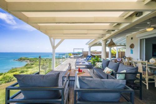 eine Außenterrasse mit Stühlen, einem Tisch und Meerblick in der Unterkunft Villa d'Happy Bay - Panoramic View of Caribbean and sunsets in Friar's Bay