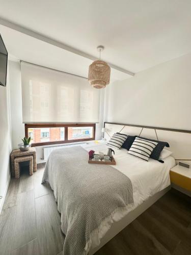a bedroom with a large white bed and a window at Apartamento Somo Playa con garaje, Cantabria in Somo