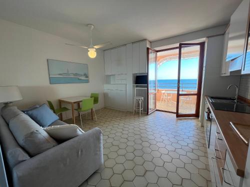 a living room with a couch and a kitchen with the ocean at Fortino Fronte Mare in Fossalòn