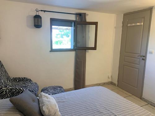 a bedroom with a bed and a window and a door at Le gîte des Oliviers in Forcalquier