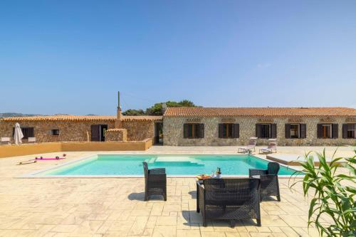 a swimming pool with chairs and a table in front of a building at Dimora PietrAnna - Paradiso in Sardegna in Li Valcaggi