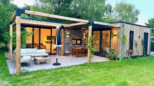 a wooden pergola with a couch and a table at De Krukel in Westermient