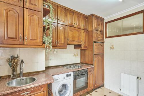 a kitchen with wooden cabinets and a sink and a dishwasher at The Nest - by Wehomes in Santander