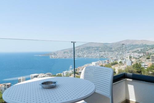 a table and chairs on a balcony with a view of the ocean at Hilltop Heaven Hotel in Sarandë