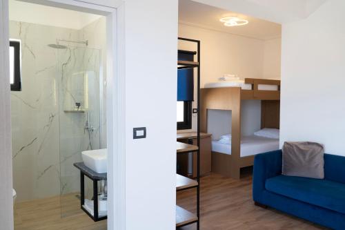 a living room with a blue couch and a bathroom at Hilltop Heaven Hotel in Sarandë