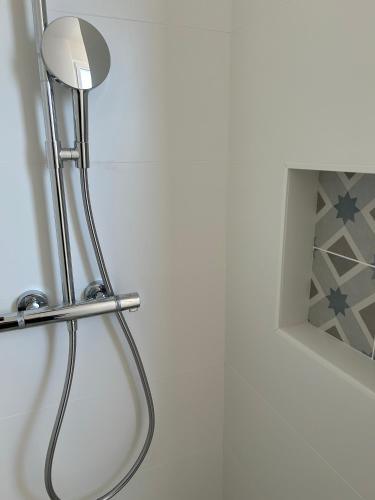 - un pommeau de douche dans la salle de bains à côté d'un miroir dans l'établissement Le Clos Morgane Villa Mélissa, à Bretignolles-sur-Mer