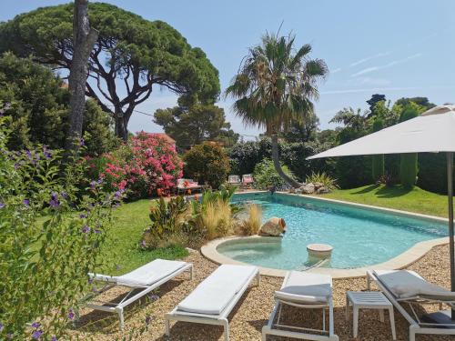 una piscina con sillas y una sombrilla en un patio en Lou Pitchoun, en Saint-Aygulf