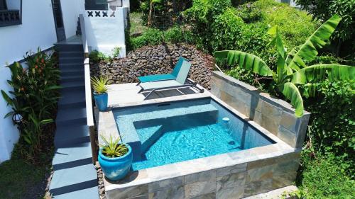 a swimming pool with a chair in a garden at Villa T4 avec piscine, 6 à 8 personnes in Schœlcher