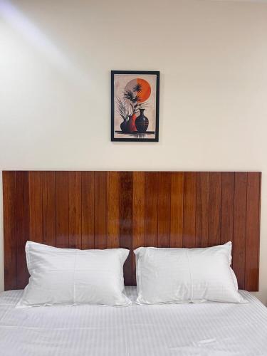 a white bed with a wooden headboard and white pillows at Ram Residency chengalpattu in Ottivākkam