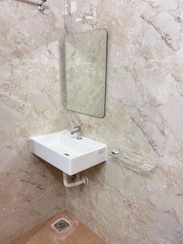 a bathroom with a sink and a mirror on a wall at Ram Residency chengalpattu in Ottivākkam