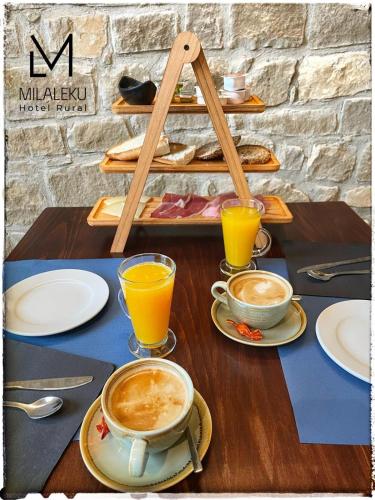 a table with cups of coffee and plates of food at Hotel Rural Milaleku in Ecala