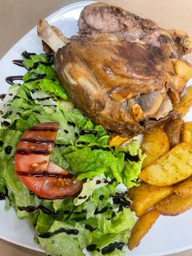a plate of food with meat and salad and potatoes at Hotel Rural Milaleku in Ecala