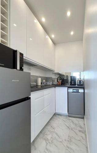 - une cuisine blanche avec des armoires blanches et des appareils noirs dans l'établissement Apartment My HOME Eiffel Tower View, à Paris