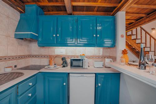 a kitchen with blue cabinets and a microwave at Yellow House - Casa 1 in Angra do Heroísmo