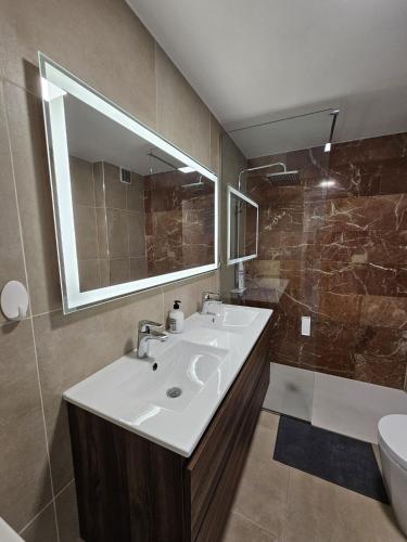 ein Badezimmer mit Waschbecken, Spiegel und Dusche in der Unterkunft Dinas KOKA Resort in Playa del Ingles