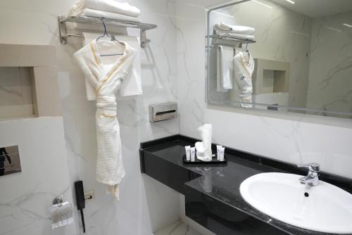 a white bathroom with a sink and a mirror at Armada Avenue Hotel Amman in Amman