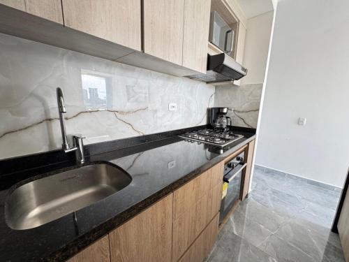 a kitchen with a sink and a stove at Monteazul1206- Lindo y amplio apartamento con piscina gym in Armenia