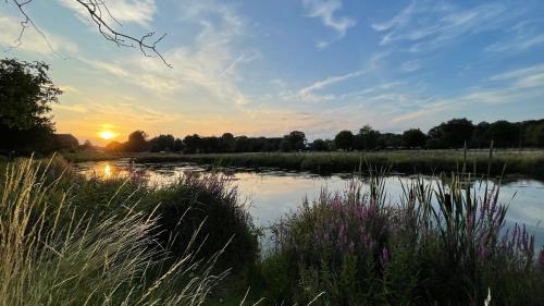 a view of a pond with the sunset in the background at Ferienhaus an der Niers in Weeze