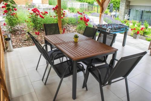 a wooden table and chairs on a patio with flowers at Oázis Tapolca Apartman in Miskolctapolca