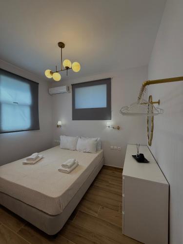 a white bedroom with a bed and a table at Almyrolithos in Gythio