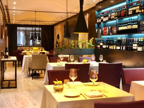 a restaurant with tables and chairs with wine glasses at Hotel Indigo Rome - St. George by IHG in Rome